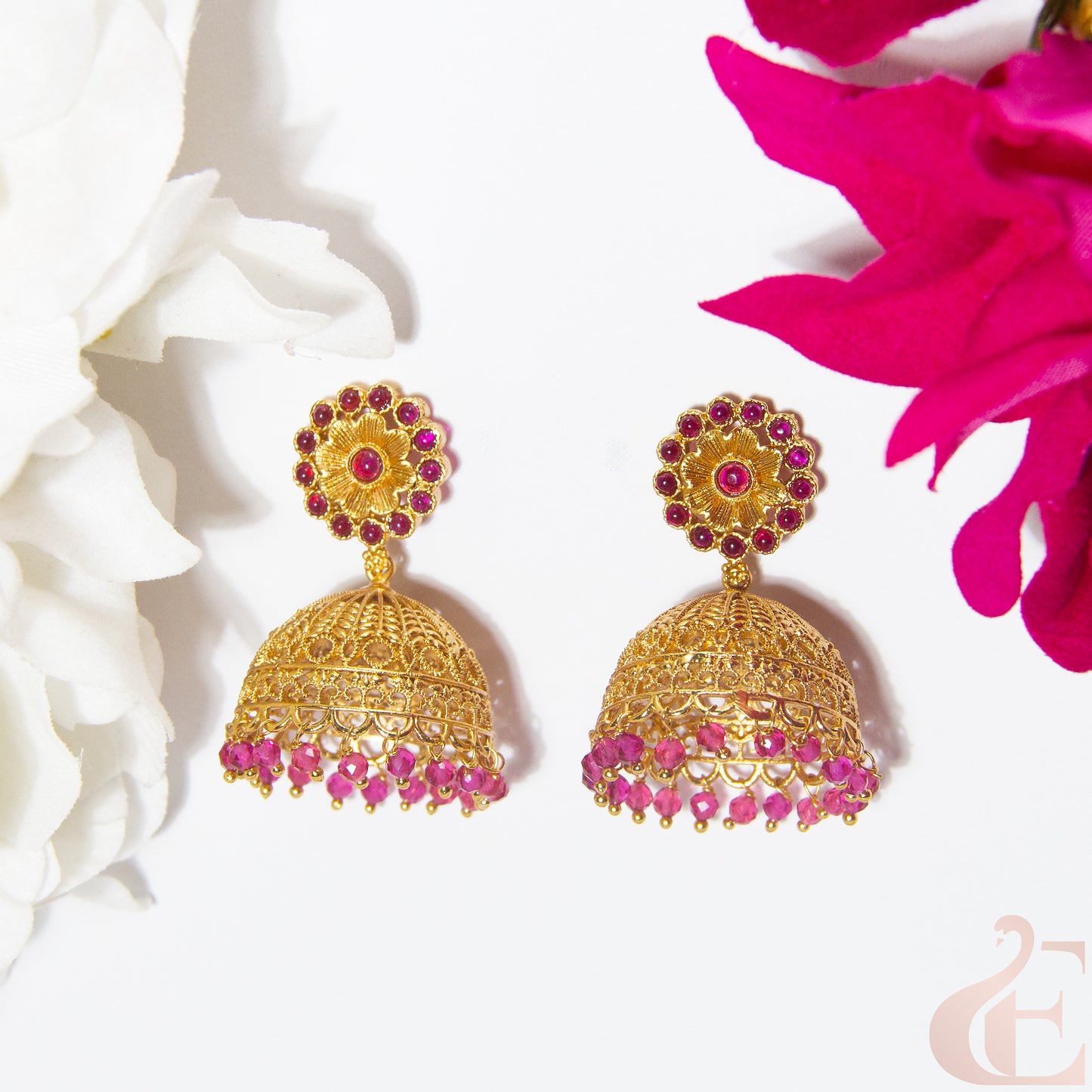 Gold and pink earrings on a white and ruby floral background