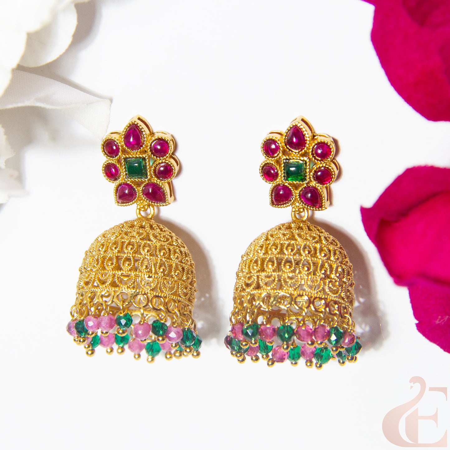 Gold earrings with ruby green gemstones on a white background