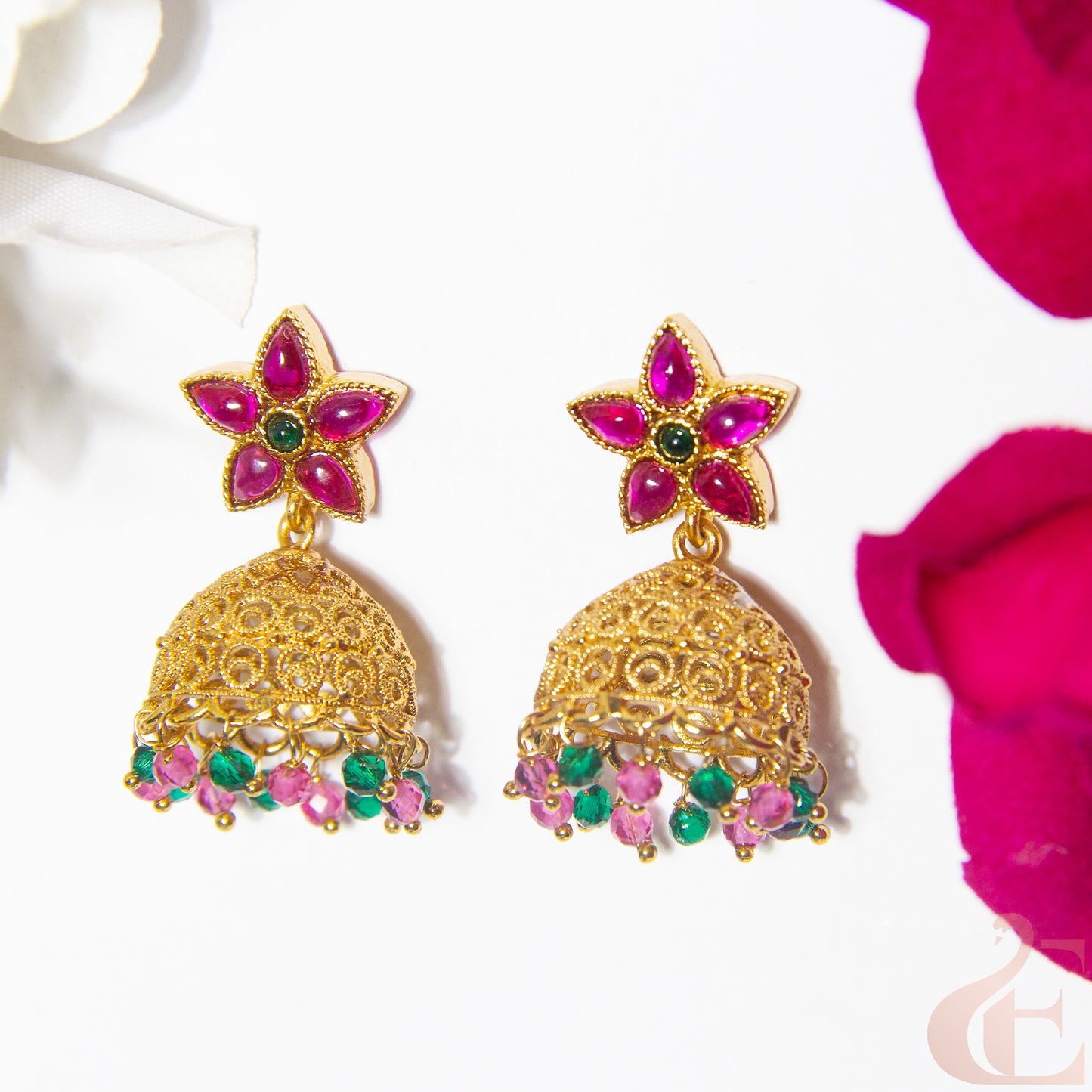 Gold and ruby green earrings on a white background