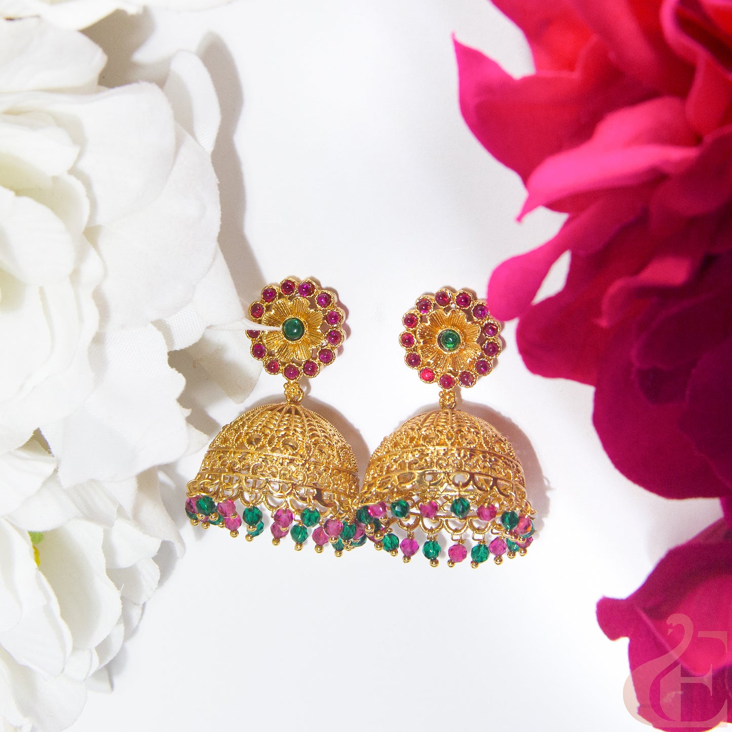 Gold earrings with gemstones on a white and Ruby green floral background