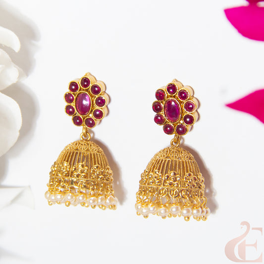 Gold earrings with ruby gemstones on a white background