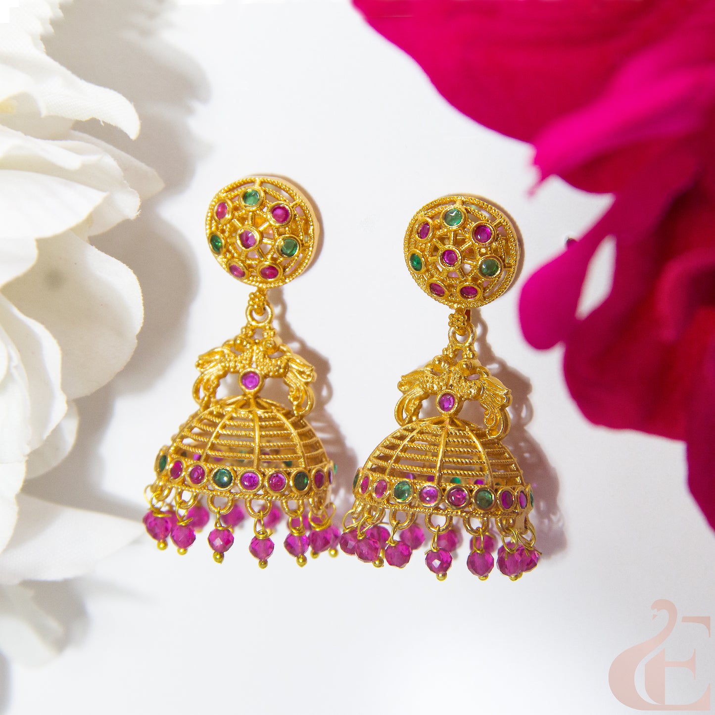 Gold earrings with colorful beads on a white and ruby floral background