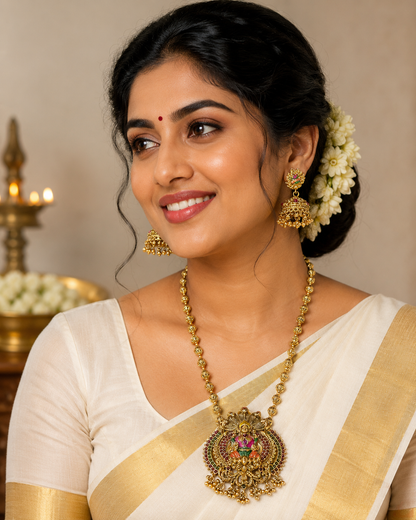 Woman wearing traditional jewelry and a saree with a neutral background