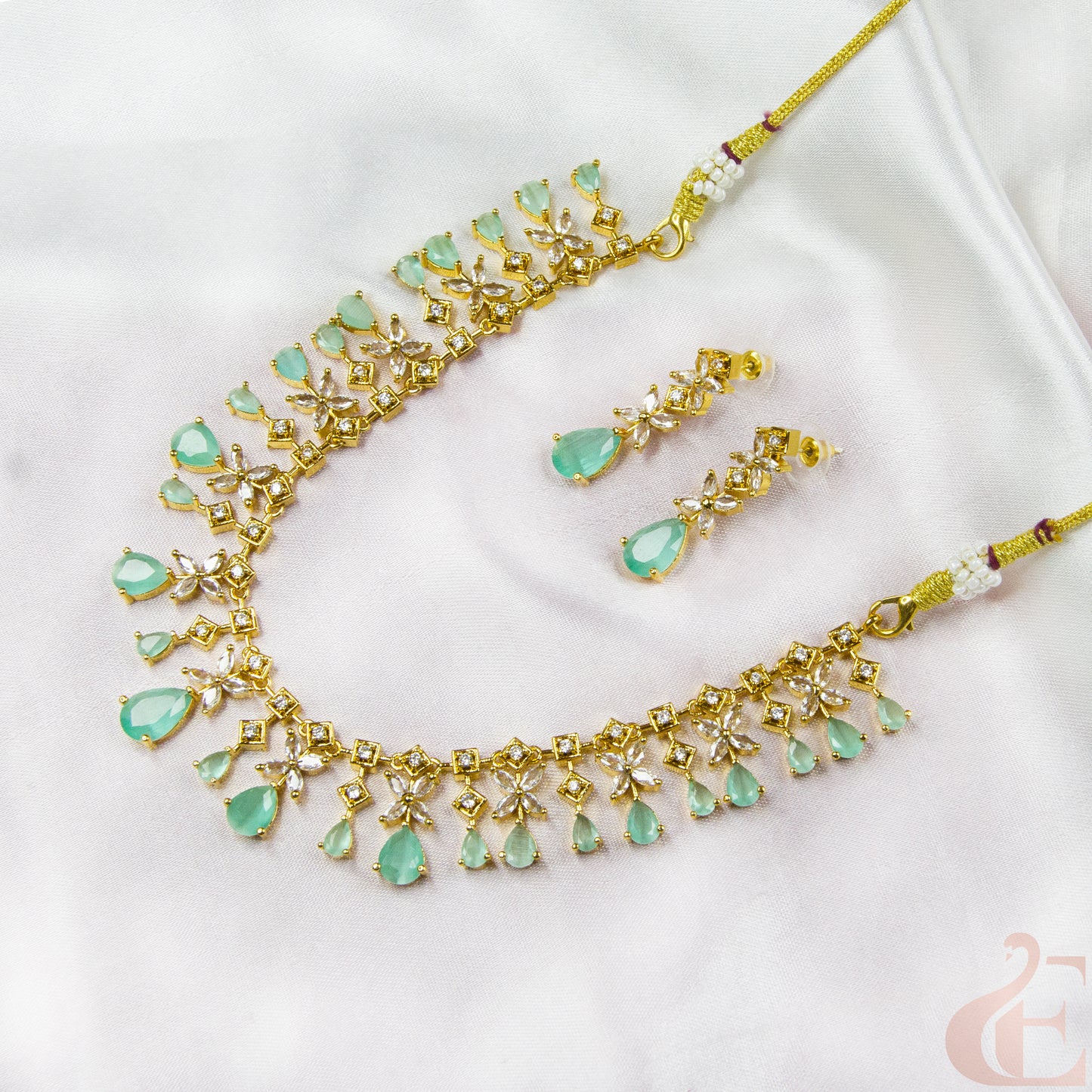 Gold necklace with green gemstones on a white background