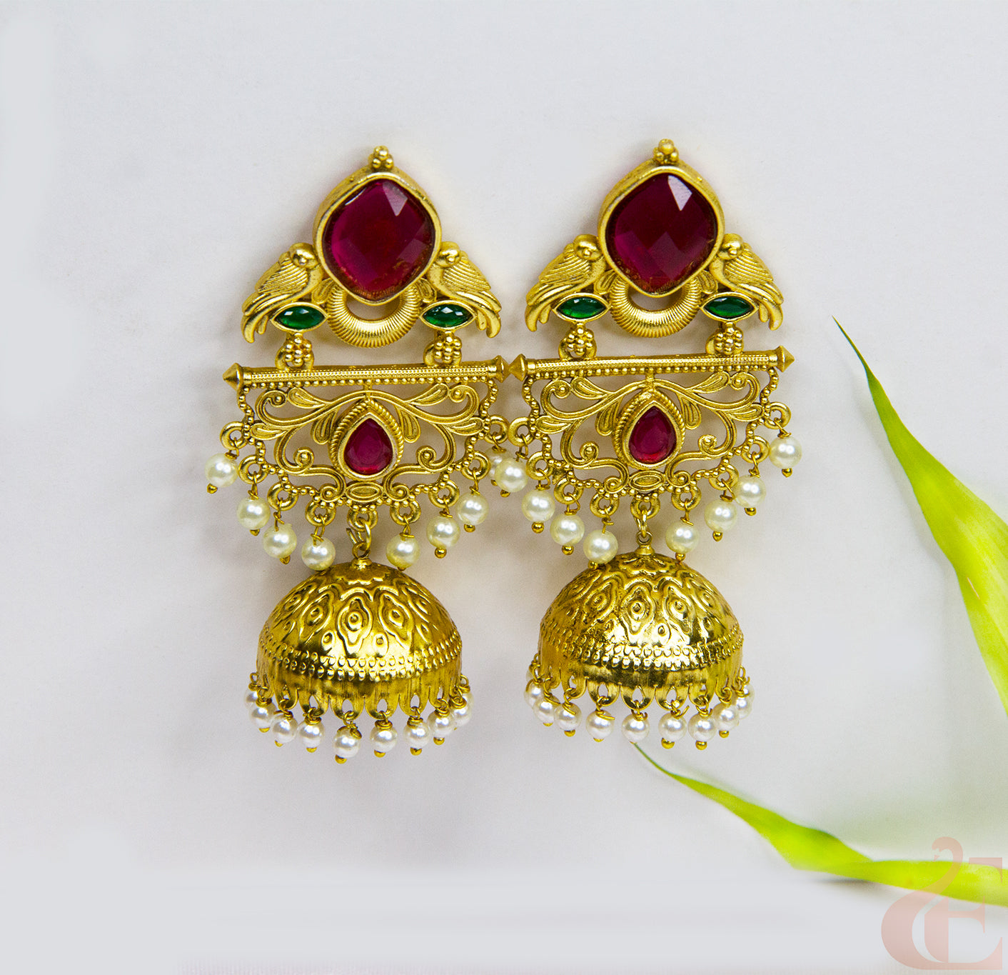 Gold earrings with red and green gemstones on a white background