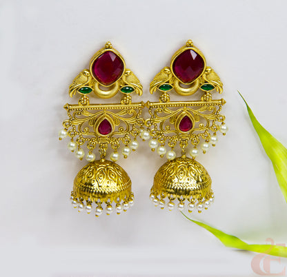 Gold earrings with red and green gemstones on a white background