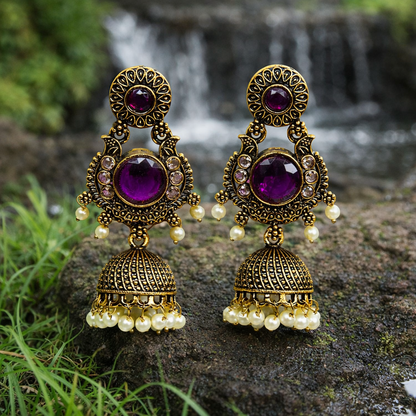 Ornate earrings with purple gemstones and gold accents on a natural background