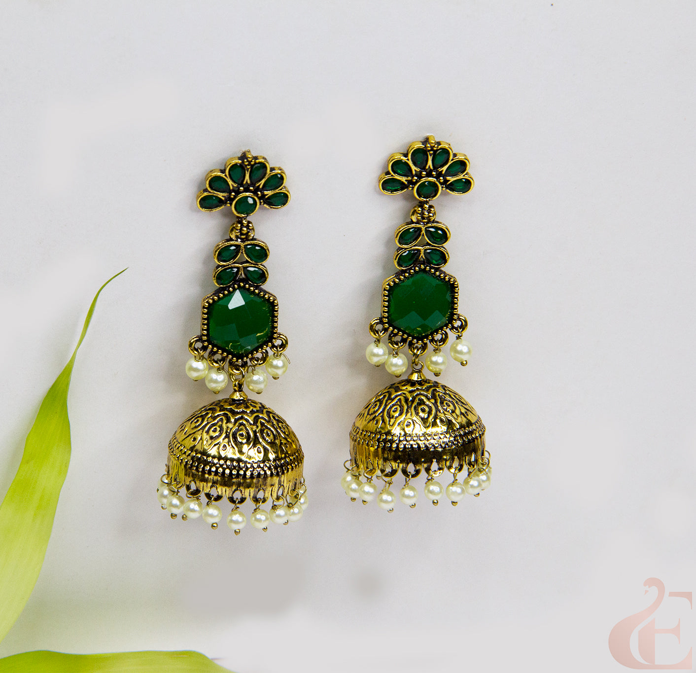 Gold and green earrings with pearl accents on a light background