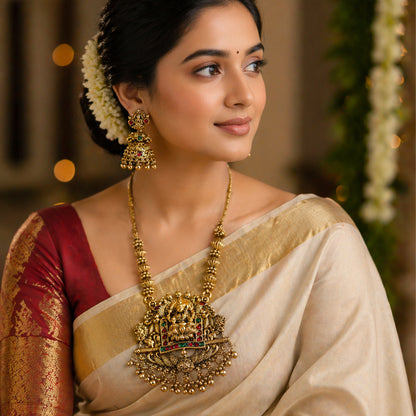 Woman wearing traditional Indian attire with gold jewelry and a blurred decorative background