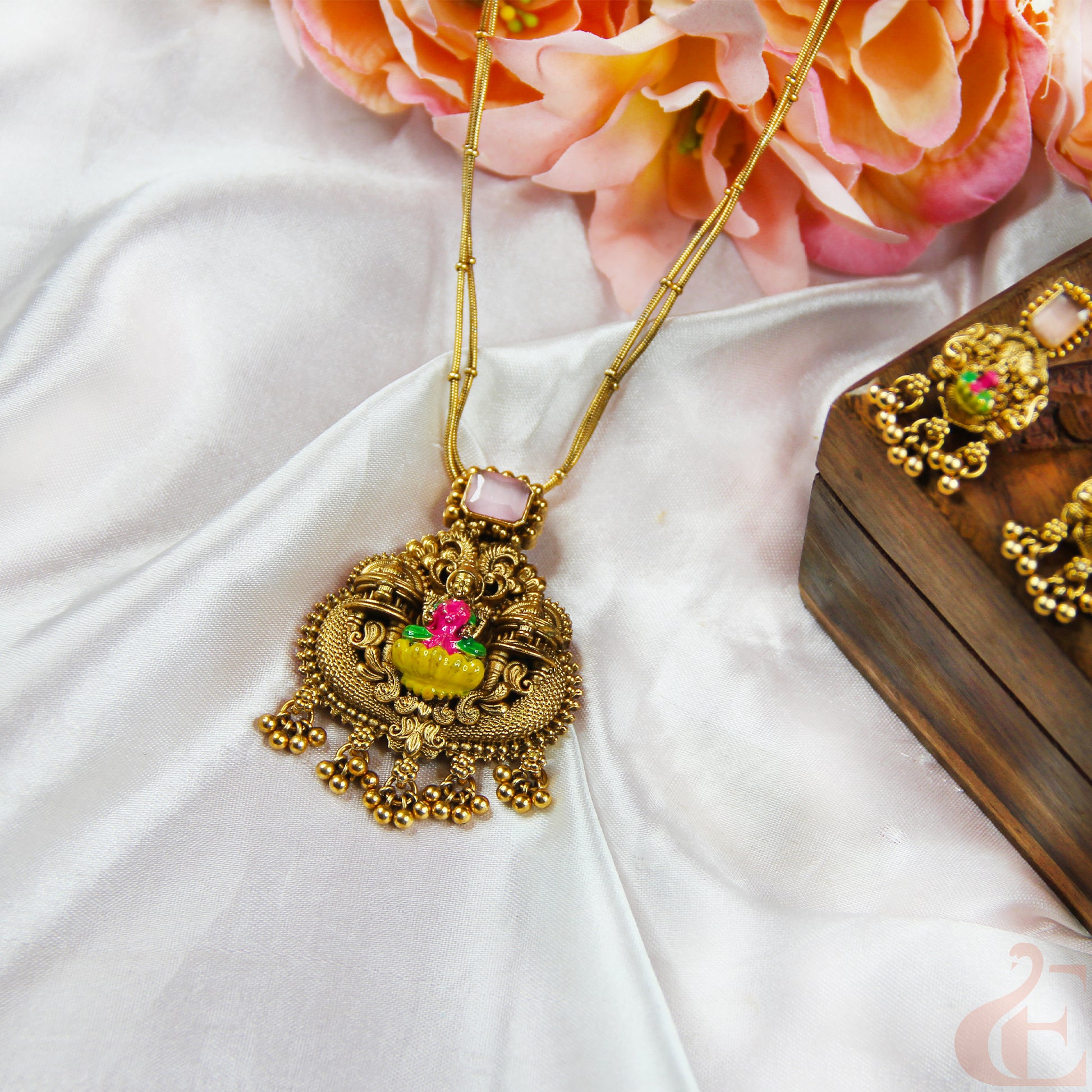 Gold necklace with decorative pendant on a white fabric background