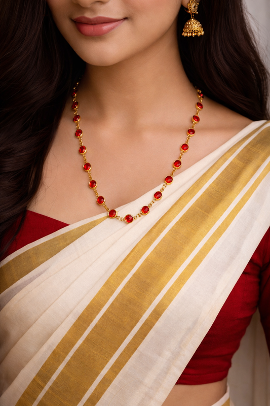 Woman wearing a red and gold saree with a matching necklace.