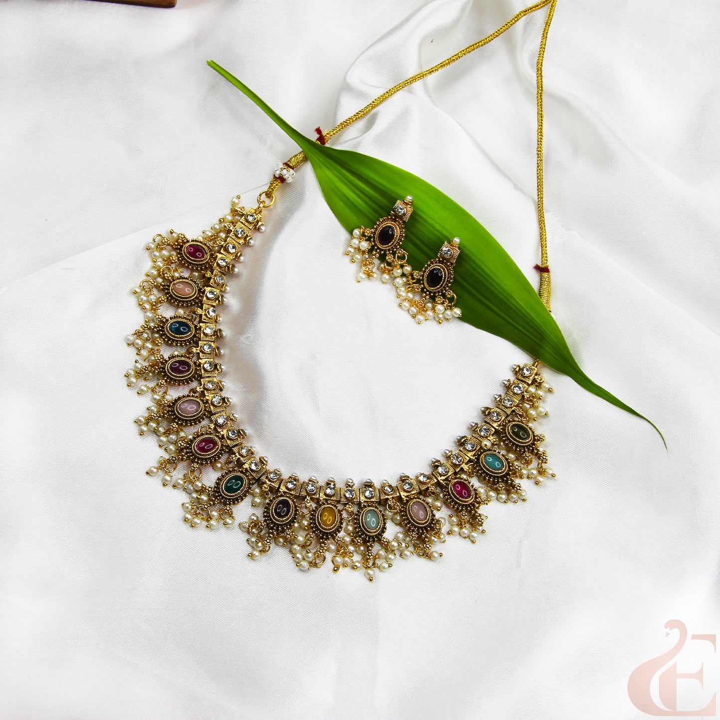 Ornate necklace with colorful stones on a white fabric background