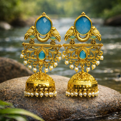 Gold and turquoise earrings on a rock with a natural background