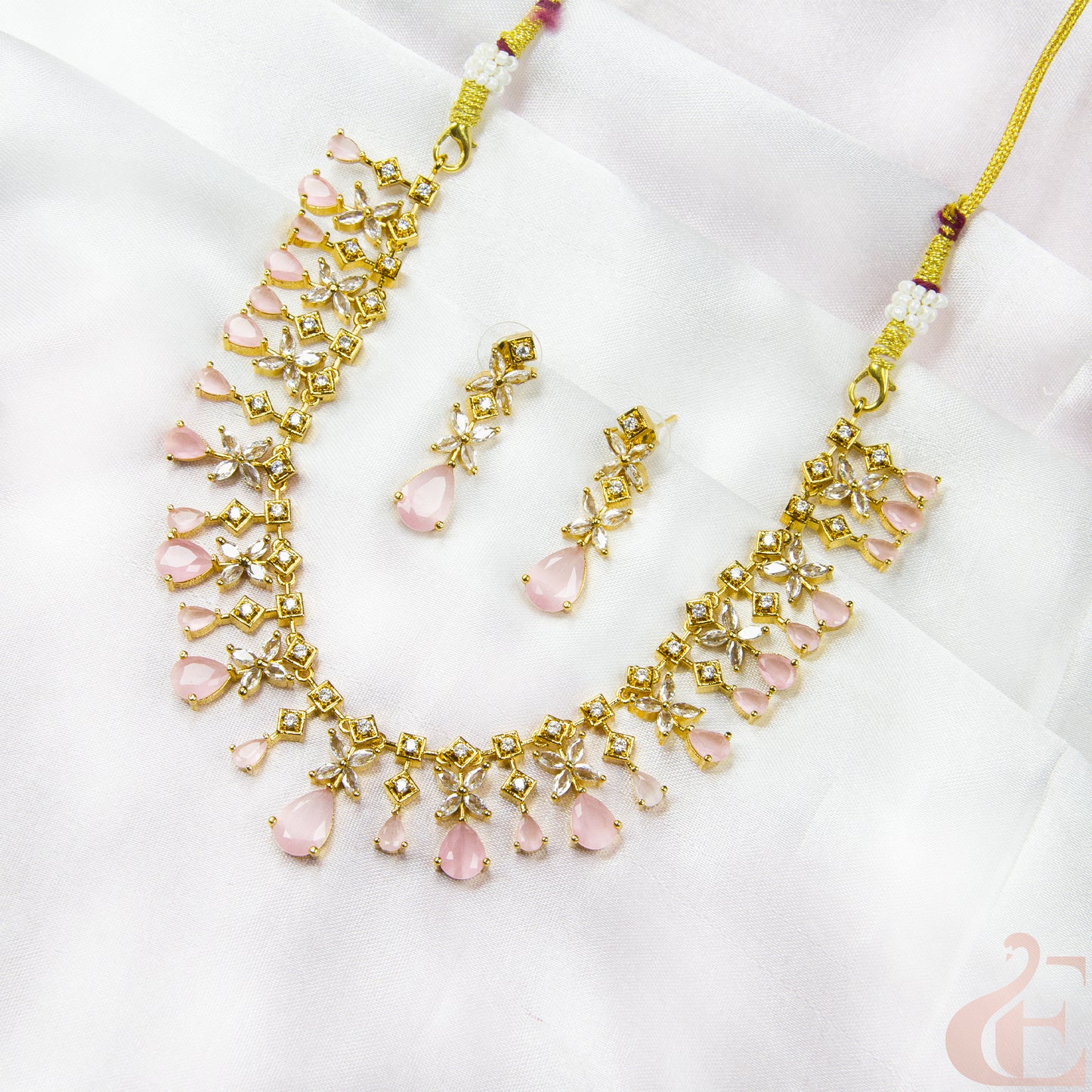 Gold necklace with pink stones on a white background