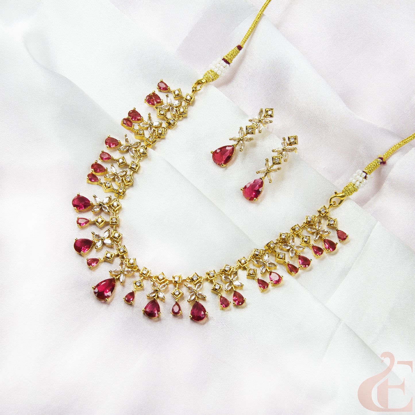 Gold necklace with red gemstones on a white fabric background