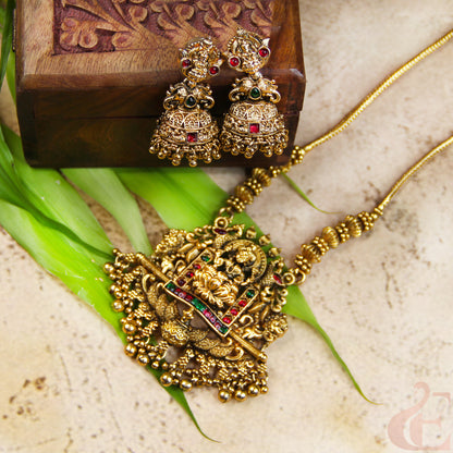 Gold necklace and earrings on a textured surface with green leaves