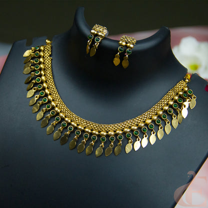 Gold-toned traditional necklace and matching earrings displayed on a black jewelry bust. The necklace features multiple rows of gold leaf-shaped charms, small green stone accents, and a beaded chain.