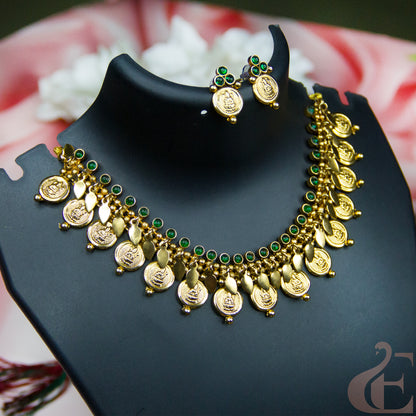Gold-toned traditional necklace and matching earrings displayed on a black jewelry bust. The necklace features multiple round coin-like charms, small gold leaf-shaped drops, and rows of green stone accents.