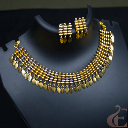 Gold-toned traditional necklace and matching earrings displayed on a black jewelry bust against a dark background.