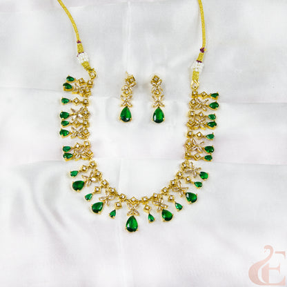 Gold necklace with green gemstones and matching earrings on a white background