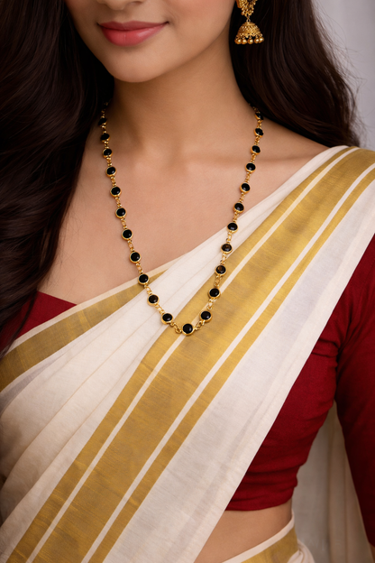 Woman wearing a traditional saree with a gold and white border, featuring a necklace with black beads.
