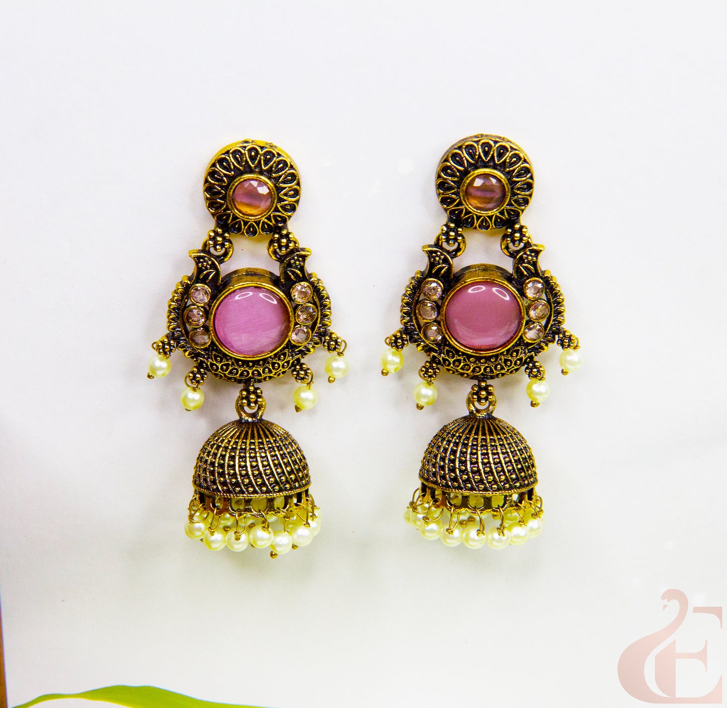Ornate earrings with pink gemstones and gold accents on a white background