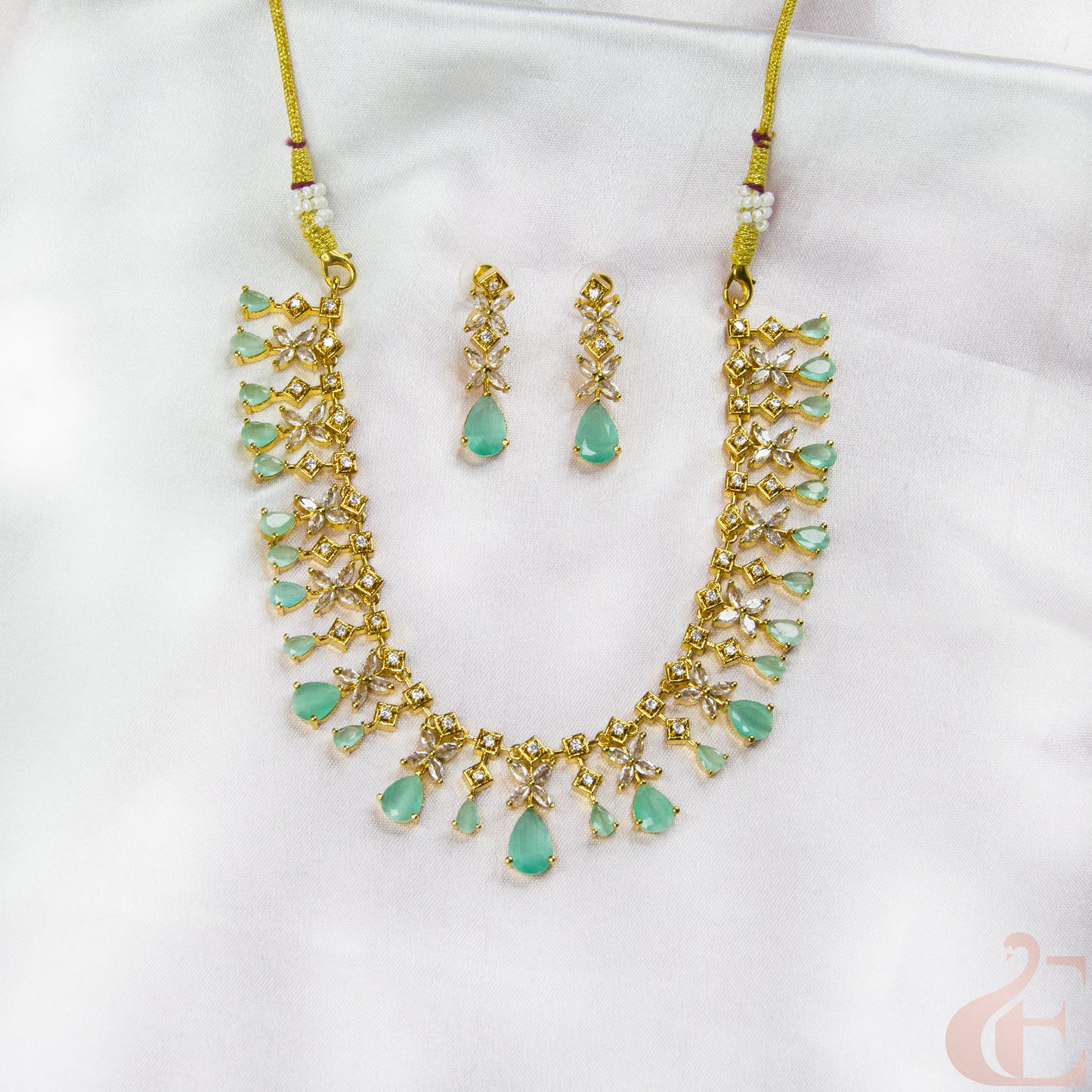 Jewelry set with necklace and earrings featuring green stones on a white background