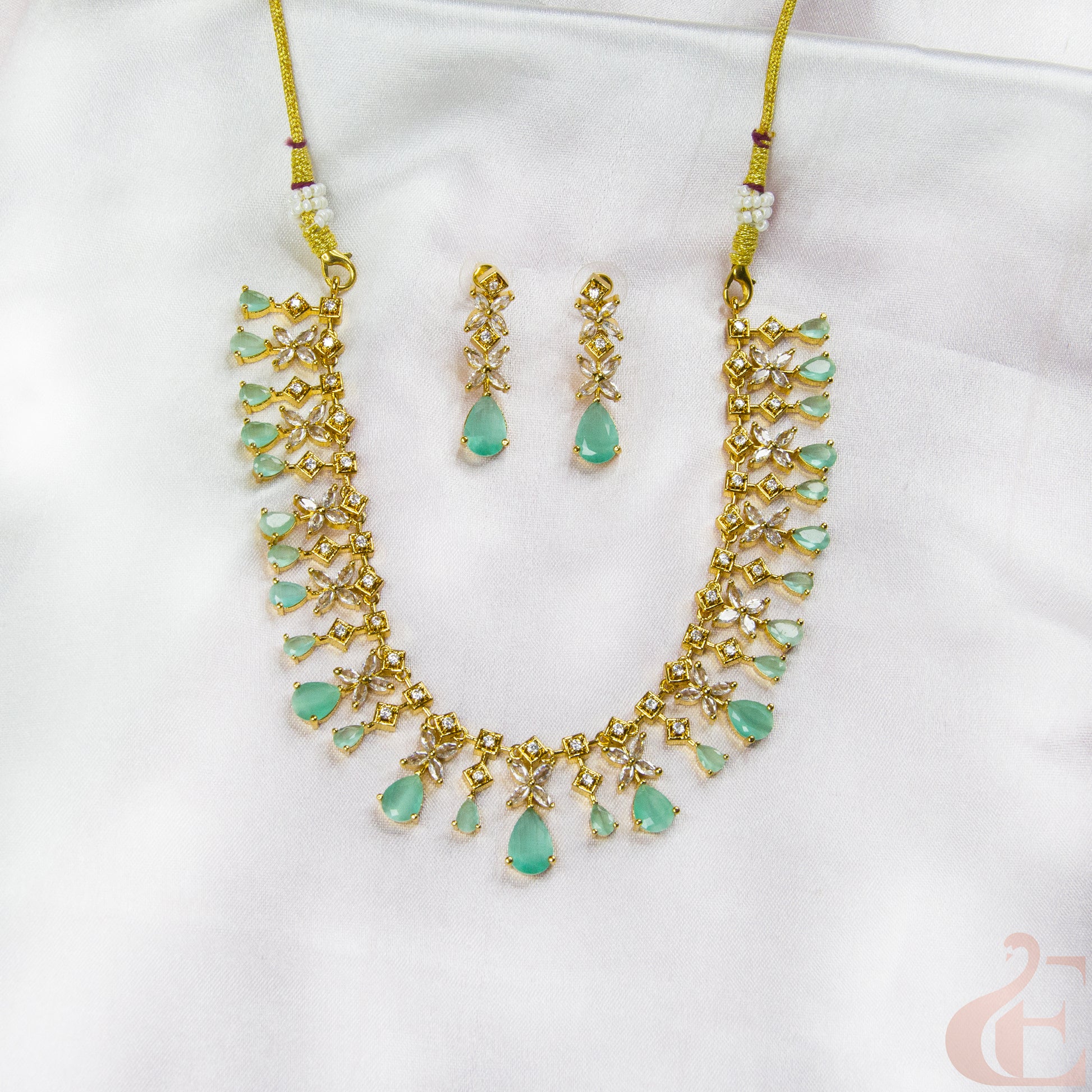 Jewelry set with necklace and earrings featuring green stones on a white background
