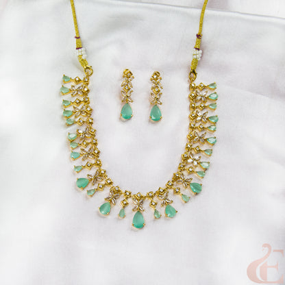 Jewelry set with necklace and earrings featuring green stones on a white background