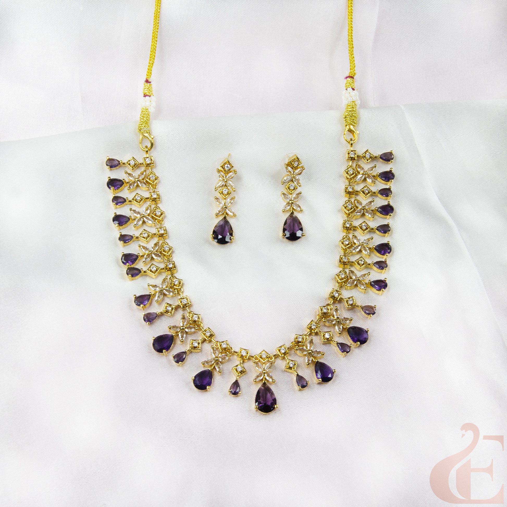 Jewelry set with necklace and earrings featuring purple stones on a white background