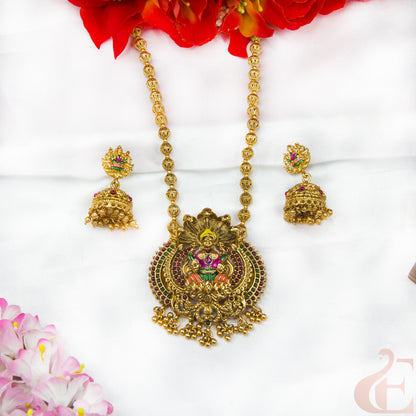Gold necklace with pendant and earrings on a white background with flowers.