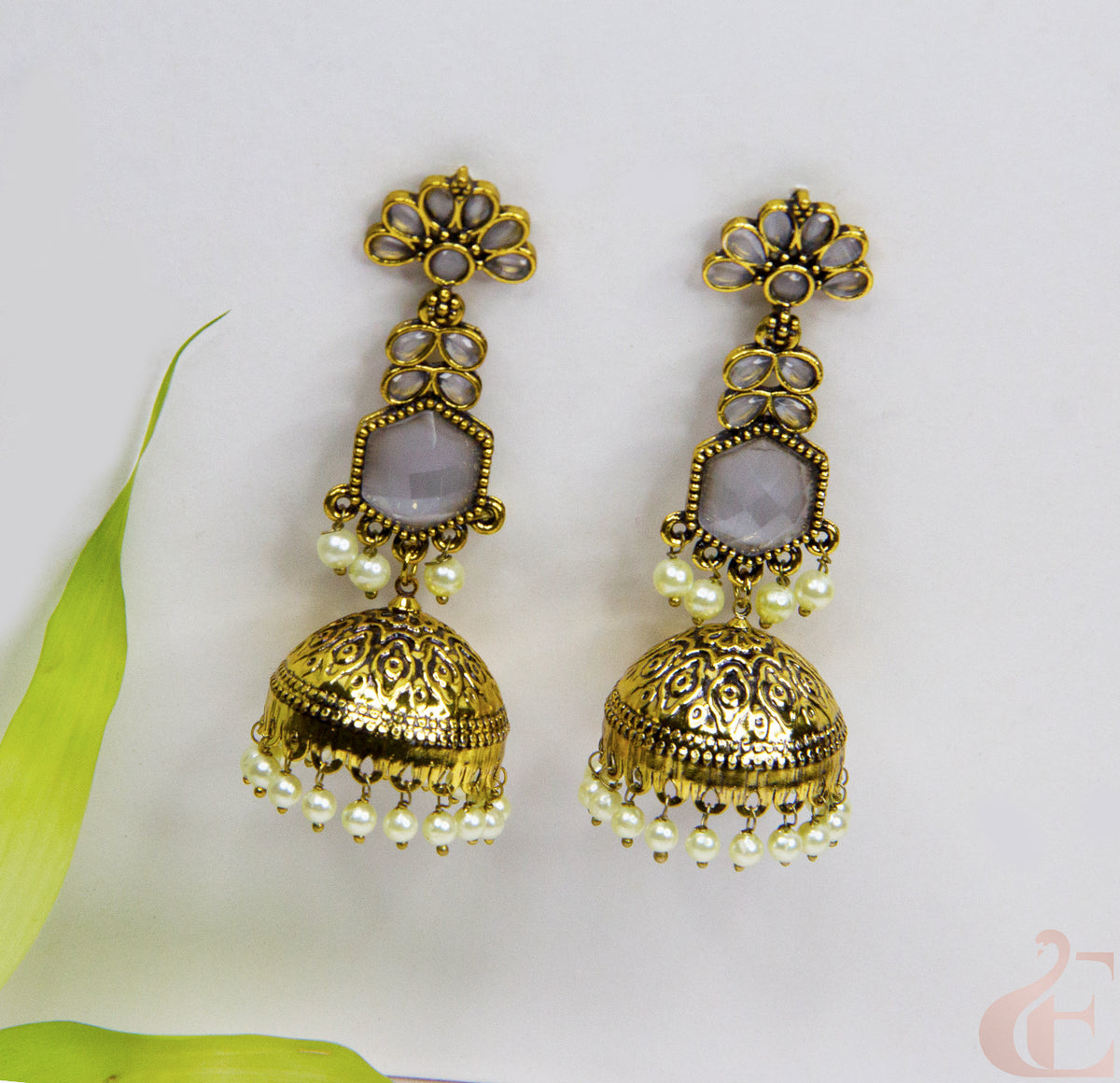 Gold earrings with pearl-like beads on a light background