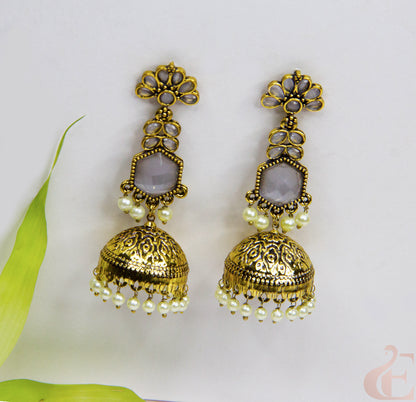 Gold earrings with pearl-like beads on a light background