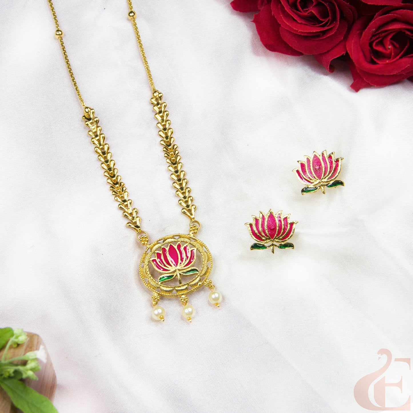 Gold necklace and earrings with pink floral designs on a white background