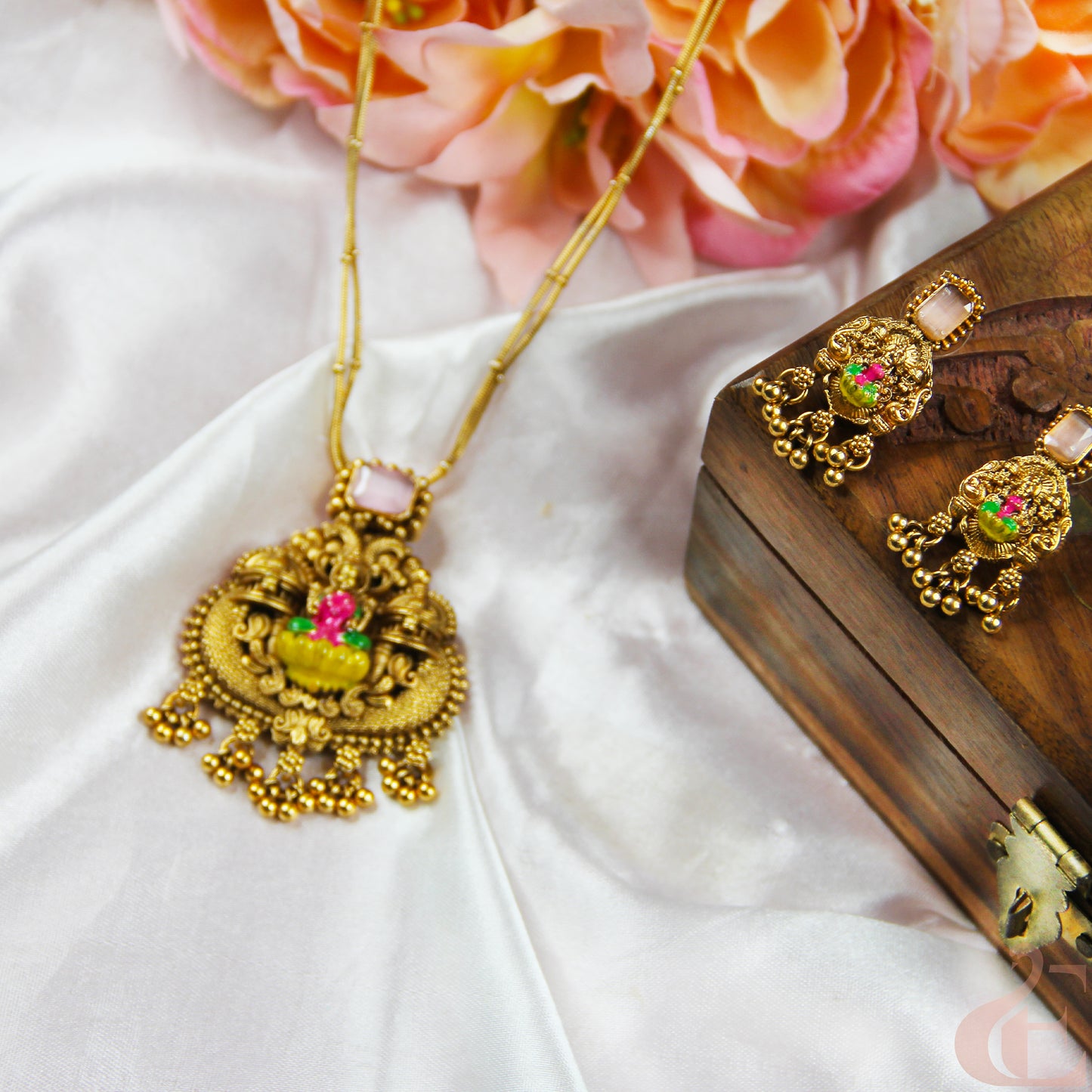 Gold necklace with floral pendant on a white fabric background