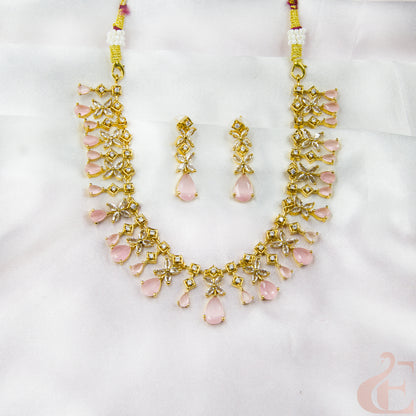 Gold necklace and earrings with pink stones on a white background
