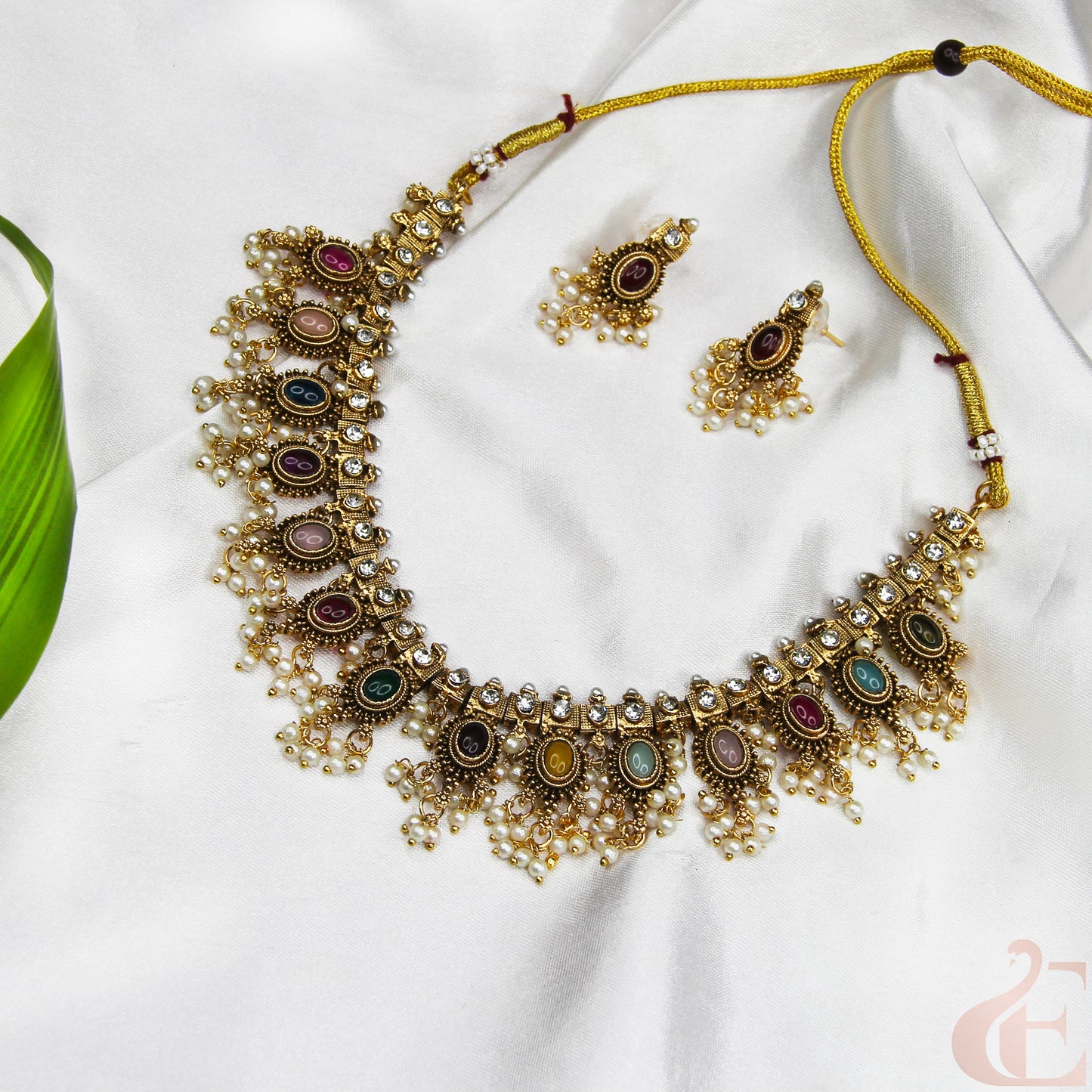 Ornate necklace with colorful stones on a white fabric background