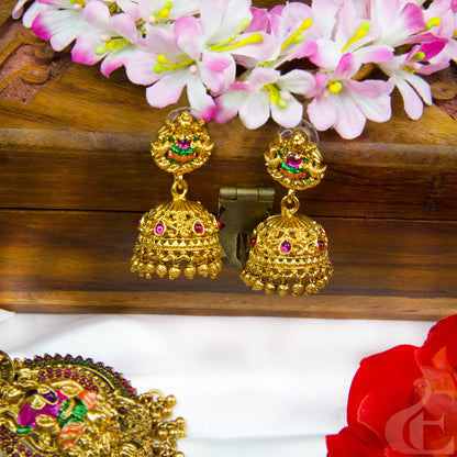 Gold earrings with gemstones on a wooden surface with flowers