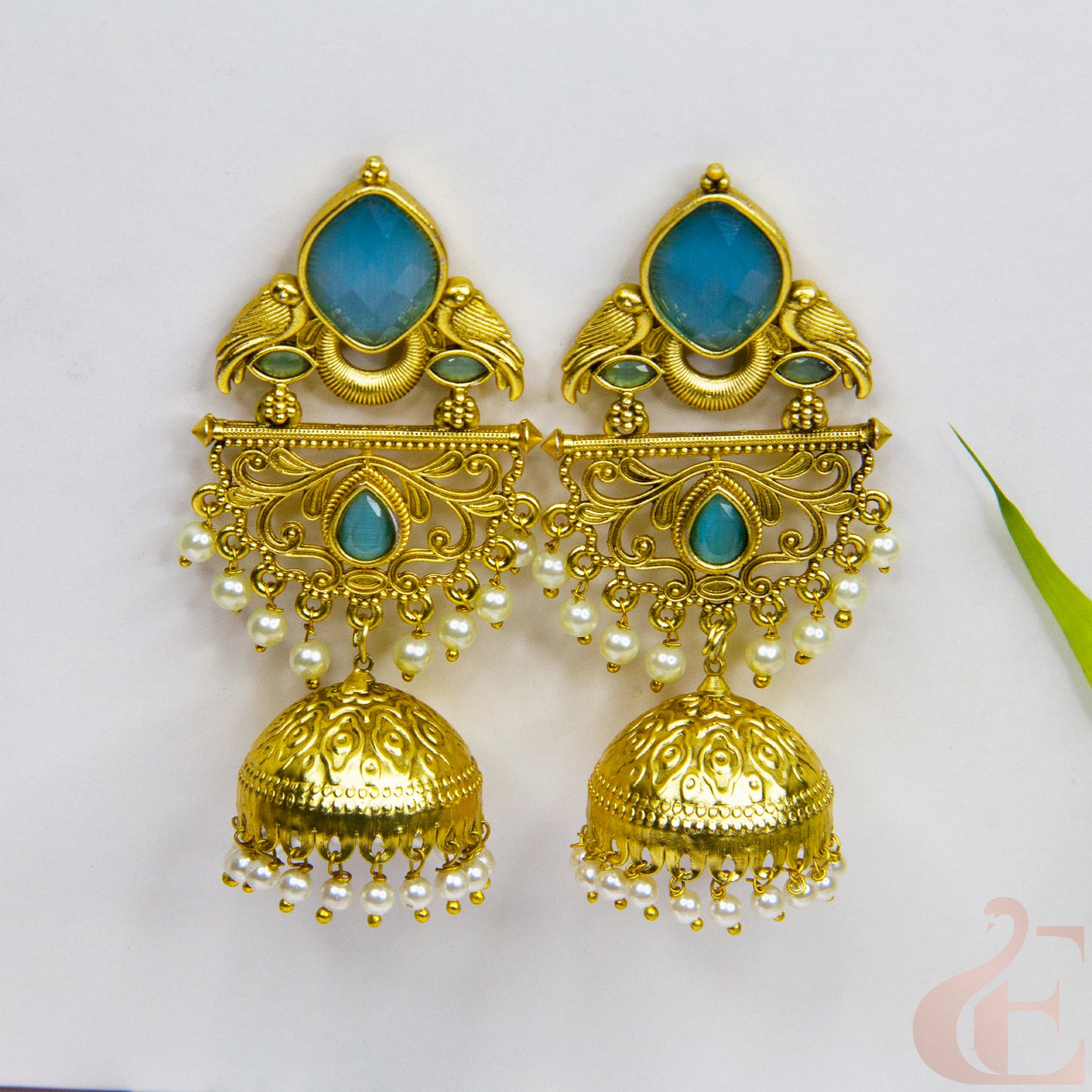 Gold and turquoise earrings with pearl accents on a white background