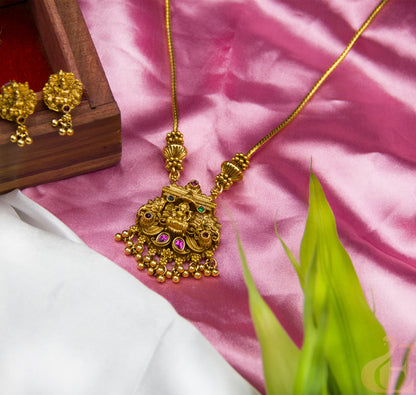 Gold necklace with intricate design on a pink fabric background