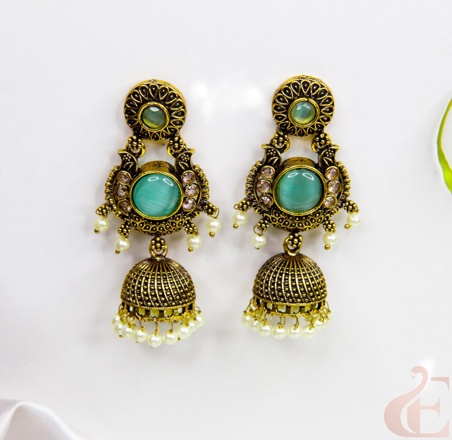 Pair of ornate earrings with turquoise stones on a white background