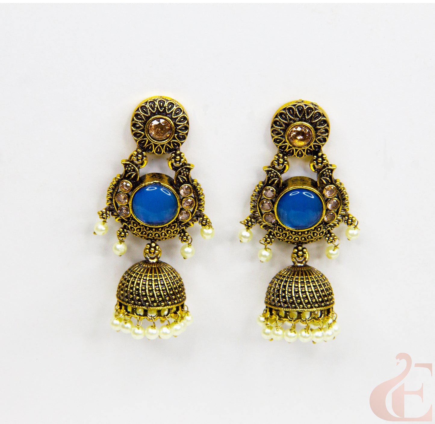 Pair of ornate earrings with blue stones on a white background
