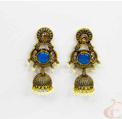 Pair of ornate earrings with blue stones on a white background