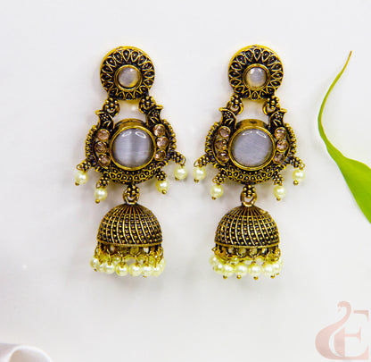 Ornate gold earrings with gemstones and pearl-like beads on a white background