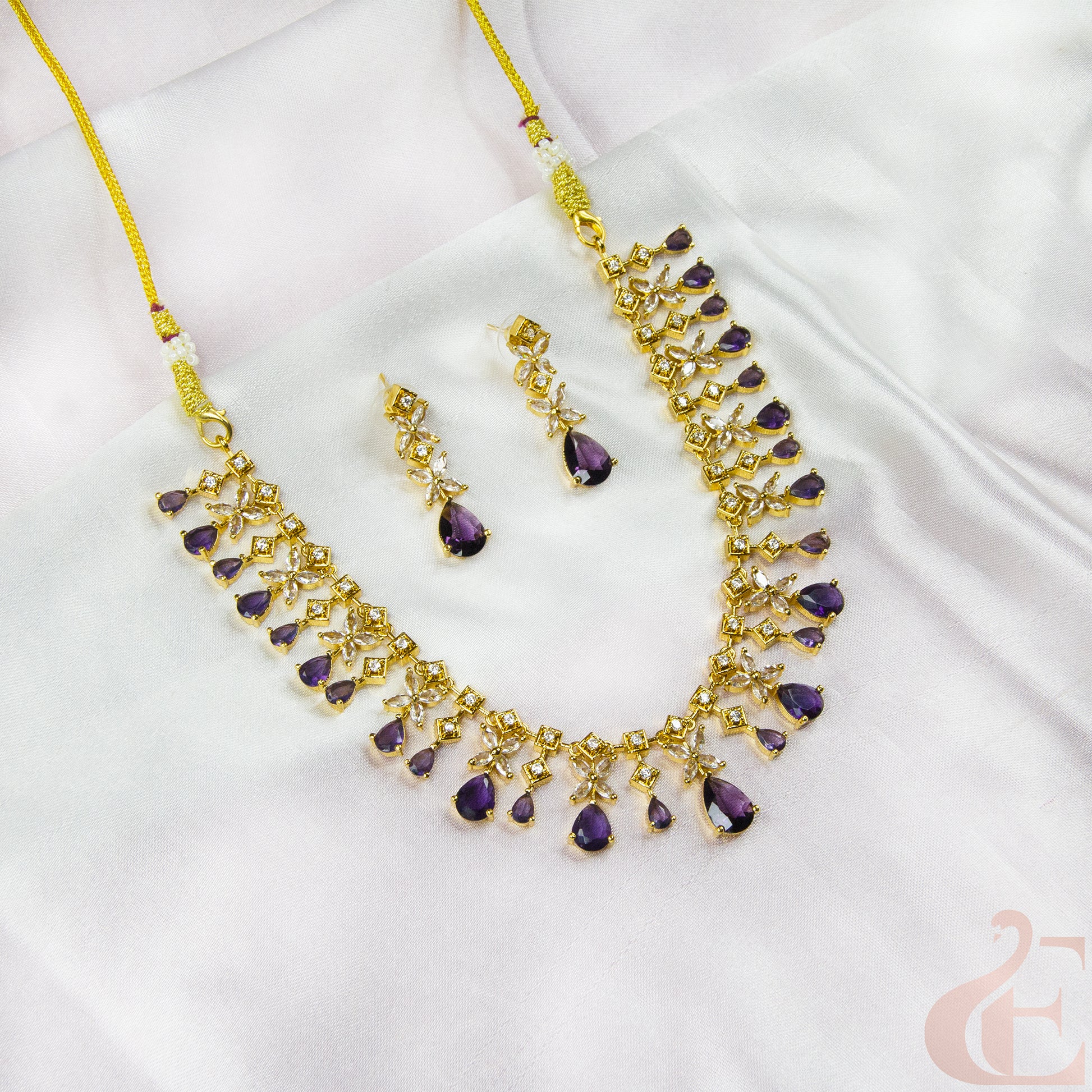 Gold necklace with purple stones on a white fabric background