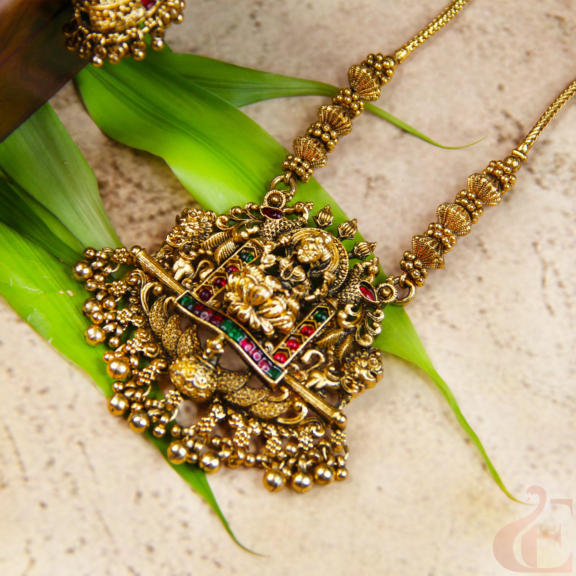 Gold necklace with intricate design on a green leaf