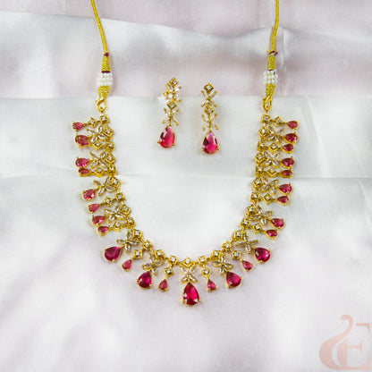 Gold necklace with red gemstones and matching earrings on a white background